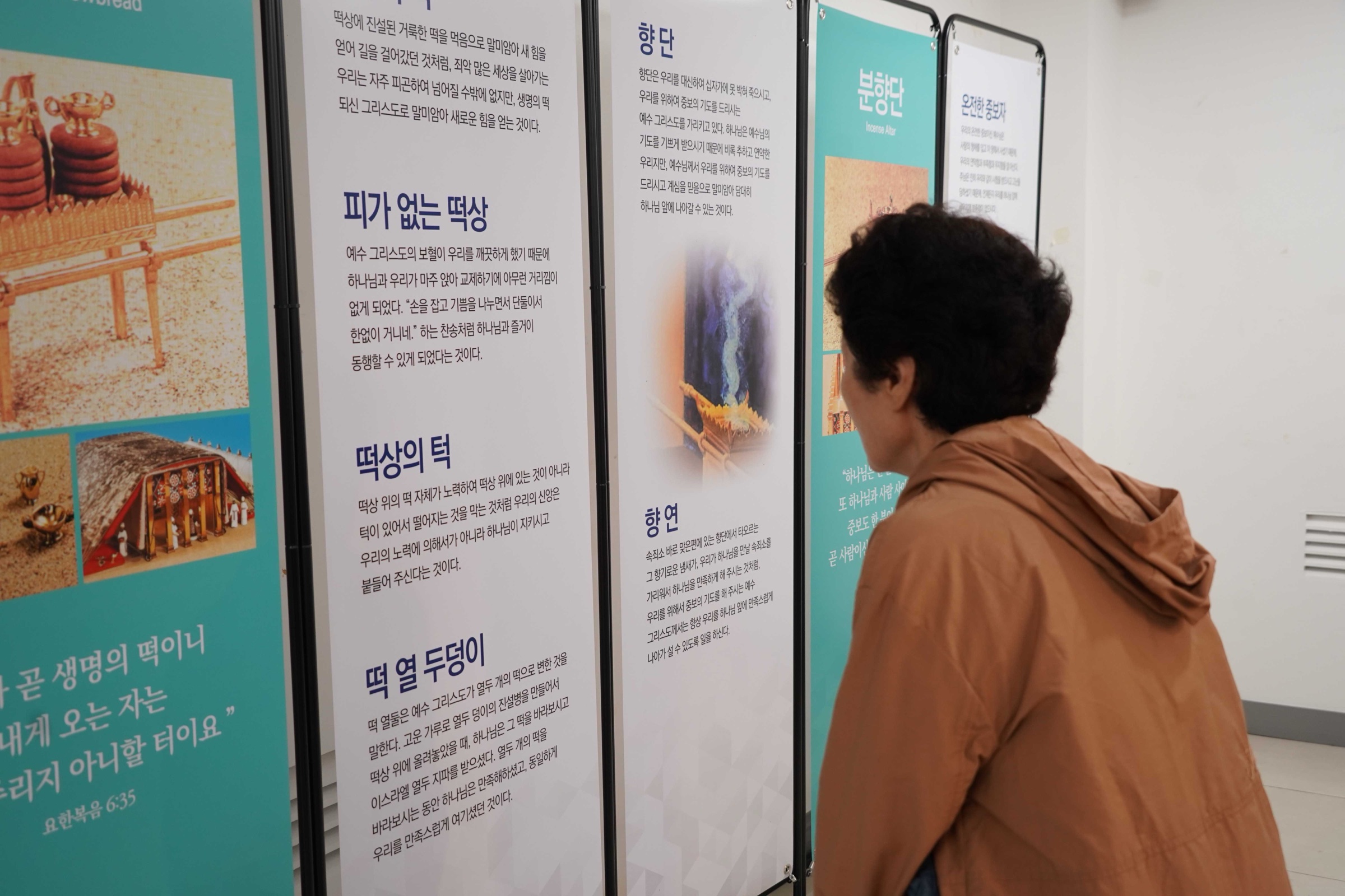 관람객이 떡상과 분향단의 의미를 설명한 전시 패널을 읽고 있다 (사진=넥스트유니온)